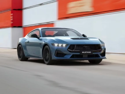 A grabber blue Mustang GT fastback at speed past shipping containers