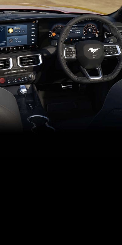 The right-hand-drive Mustang cockpit with digital cluster and red start button