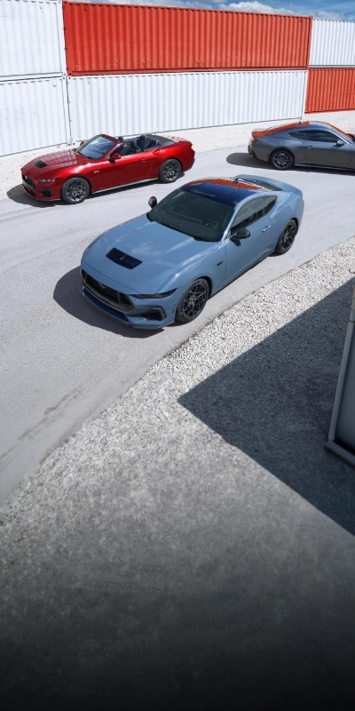 Three Mustangs angled around a container yard, blue GT in front